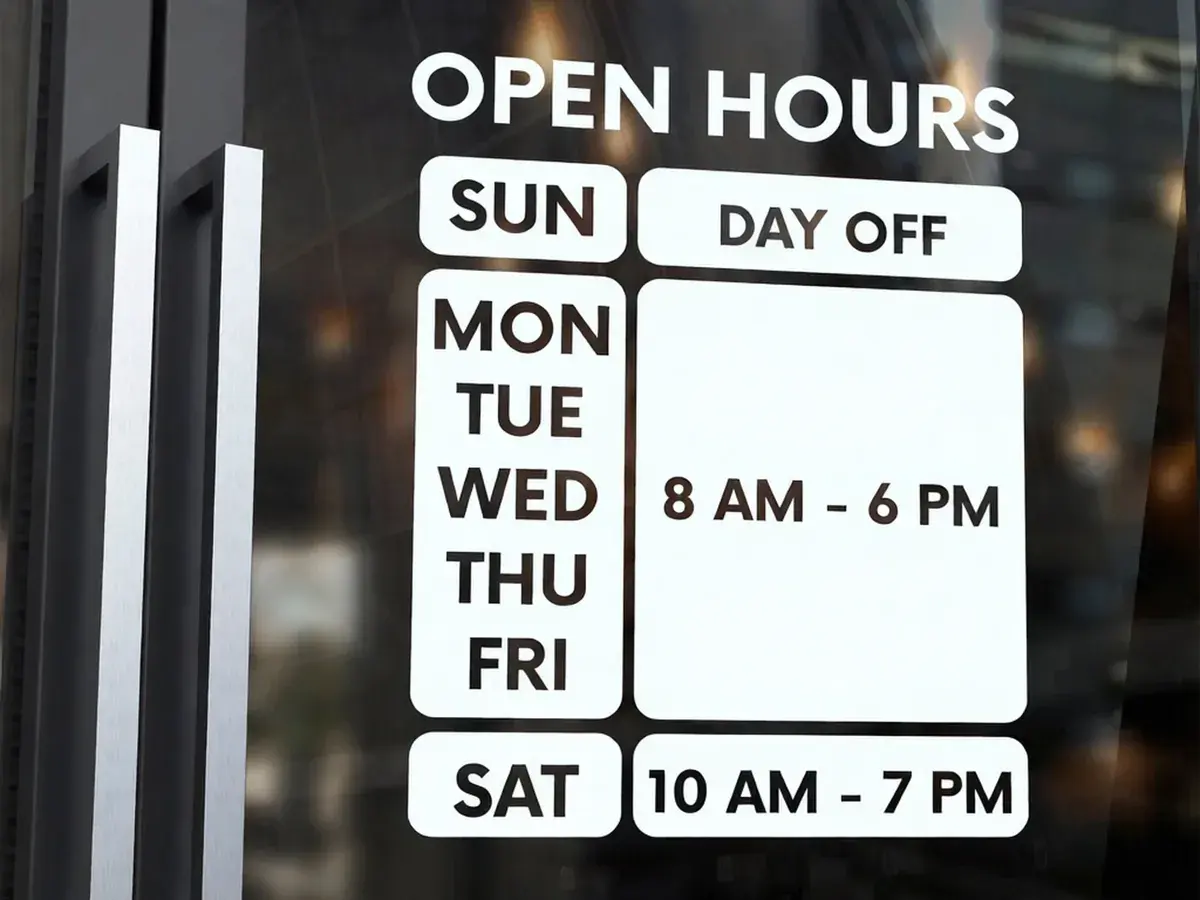 Shop opening-hours sign after the edit. The hours now read: 8 AM - 6 PM
