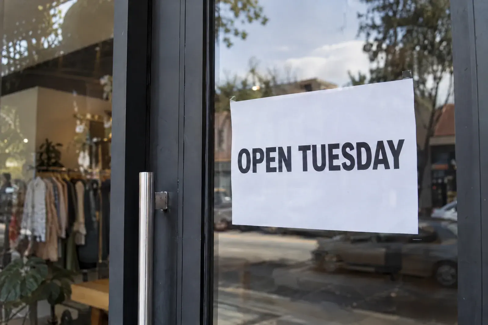 Cartel de la puerta de una tienda después de corregir la errata; dice OPEN TUESDAY